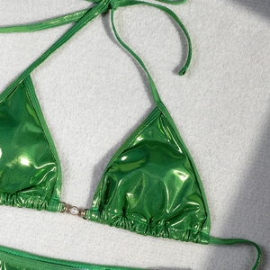 Detail of metallic green bikini top with triangle cups and a white pearl center accent