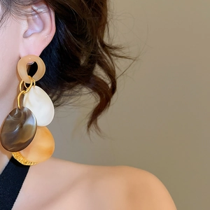 Close-up of model wearing geometric resin drop earrings in tortoiseshell and gold