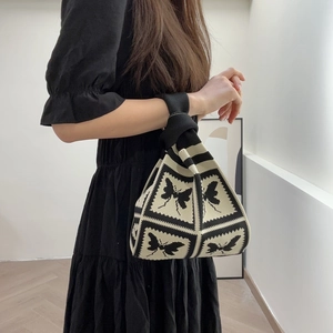 Close-up of black and white knitted floral tote bag with a unique knot handle design