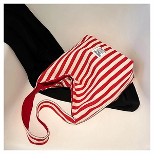Detail of red and white striped canvas tote bag with brand woven label and fabric texture