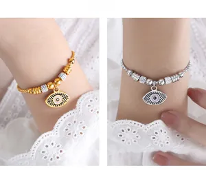 Detail of beaded evil eye bracelets in gold and silver with lilac pupils on lace sleeves