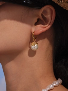 Close-up of elegant gold flower pearl earrings and baroque pearl necklace on a model