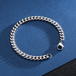 Polished silver cuban link bracelet featuring a secure lobster clasp on blue textured backdrop