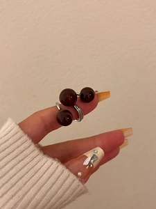 Close-up of a three-bead silver-tone layered ring with glossy brown oil-drip spheres