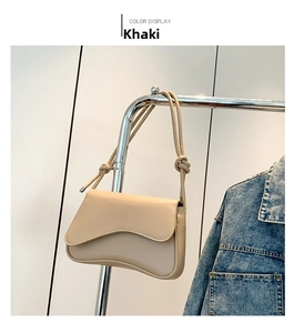 Detail view of khaki faux leather saddle bag with unique knotted strap and flap closure