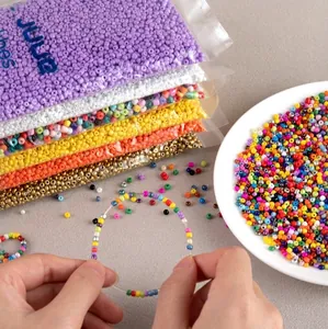 Multi-colored 2-3mm glass seed beads in transparent bags and scattered in a white dish