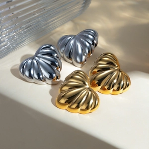 Boucles d'oreilles cœur bouffant en or 18k et argent sur une surface beige épurée