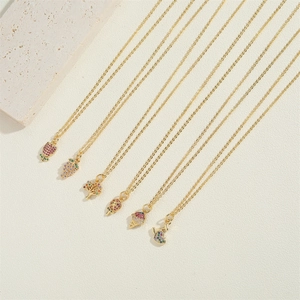 Close-up of gold necklaces with colorful zircon pendants on a natural stone surface