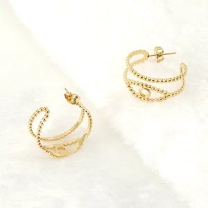 Détail de boucles d'oreilles créoles dorées avec motifs circulaires et bordures perlées