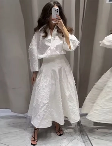 Détail d'un ensemble deux pièces blanc avec texture plumes sur chemise et jupe longue