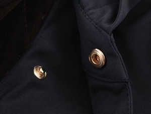 Detail of navy blue windbreaker fabric with premium gold metal button and fine stitching