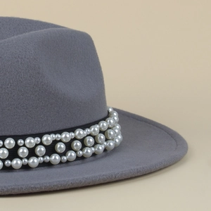 Close-up of elegant white pearls on a black ribbon band of a grey wool fedora hat