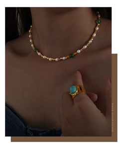Detail of freshwater pearl necklace with green agate and a turquoise gold ring on model