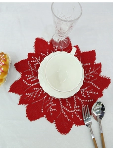 Close-up of red crochet lace placemat with intricate openwork and leaf pattern detail