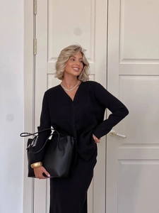 Detail of a black knit cardigan and midi skirt set with a large black leather tote bag