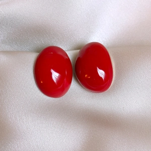 Gros plan de boucles d'oreilles vintage rouges ovales sur tissu de soie champagne