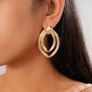 Close-up of double-loop gold metal earrings on a model showing polished finish and style