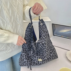 Detail of leopard print tote bag featuring textured canvas and silver metal hardware