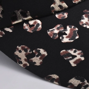 Macro detail of black leopard print fabric with golden metallic texture on a baseball cap