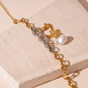 Detail of gold starfish charm and baroque pearl on mixed metal chunky chain bracelet