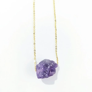Detailed view of large irregular natural purple crystal pendant with a gold chain