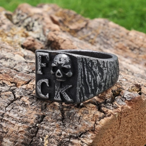 Vintage punk skull FCK letter ring in distressed stainless steel on rustic wood