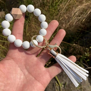 Detail of white silicone beaded wristlet keychain with wooden bead and leather tassel