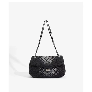 Close-up of black quilted denim fabric texture and metallic chain strap on shoulder bag