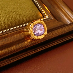 Dettaglio di un anello vintage dorato con zircone viola quadrato su cornice in legno