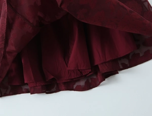 Detaillierte Makroansicht des weinroten Jacquard-Burnout-Stoffs und Saums des Kleides