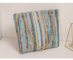 Detail of colorful striped woven tote bag with golden chain handle and metal plaque