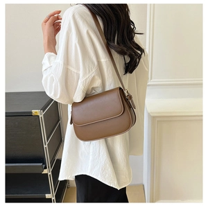 Detail of a vintage dark brown leather shoulder bag with an adjustable strap on a model