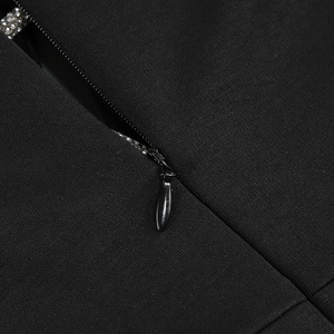 Détail macro de la fermeture éclair invisible ornée de strass brillants sur la robe noire