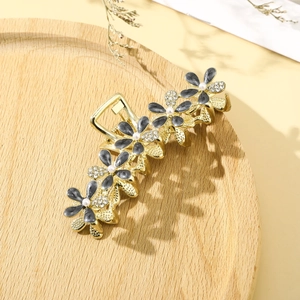Macro detail of gold floral hair claw with grey petals, pearls and crystals on wood