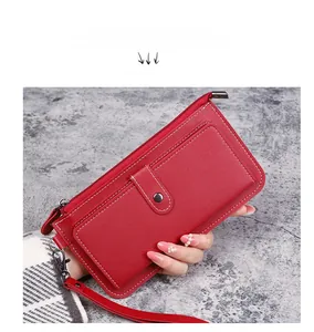 Detail view of red pebbled leather long wallet with zipper and wristlet strap