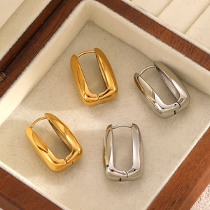 Détail de boucles d'oreilles carrées en acier doré et argenté sur support en velours