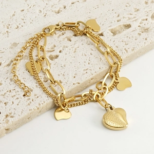 Macro shot of 18k gold heart pendants on multi-layer stainless steel chain bracelet