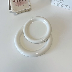 Minimalist white ceramic round plate set with thick rounded edges in a clean aesthetic
