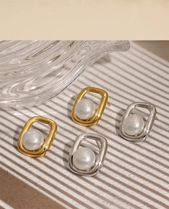 Detail of square gold and silver pearl earrings on a textured background