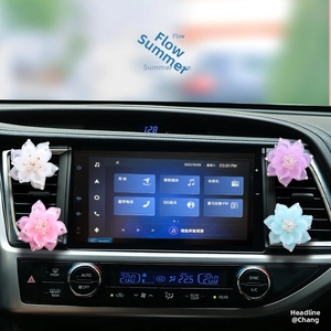 Detail of four colorful rhinestone lotus car air vent clips on a modern dashboard