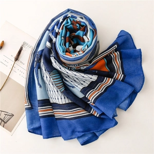 Detail of luxury silk scarf with horse print and blue borders on a white backdrop
