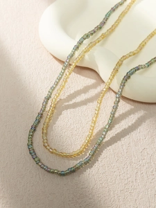 Detail shot of bohemian amber and green seed bead necklaces on a white tray