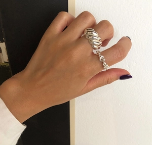 Detail view of 925 silver rings with twisted horn and chain link designs on model's hand