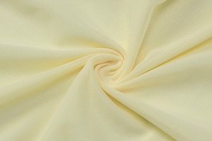 Close-up of pale yellow knitted mesh fabric texture with soft spiral folds and weaves