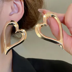 Minimalist large heart-shaped gold hoop earrings with a polished metallic mirror finish