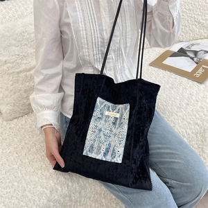 Close-up of velvet tote bag featuring blue lace embroidery details and slim shoulder strap