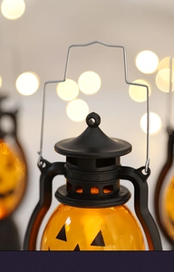 Close-up of a lit orange Halloween pumpkin lantern with a metal handle and warm glow
