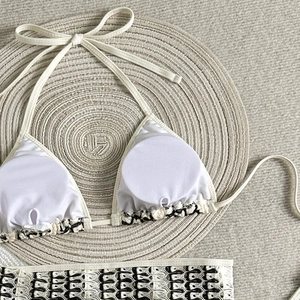 Gros plan du haut de bikini au crochet noir avec coussinets blancs sur un tapis tressé