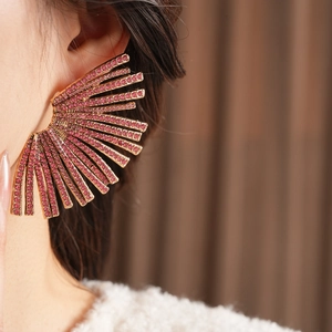 Close-up of fan-shaped radiating earrings with pink rhinestones on gold base