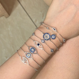 Nahaufnahme von S925 Silber Evil Eye Armbändern mit blauen Zirkonia am Handgelenk gestapelt